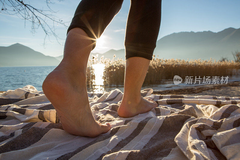 女人的腿在海滩湖边，光着脚