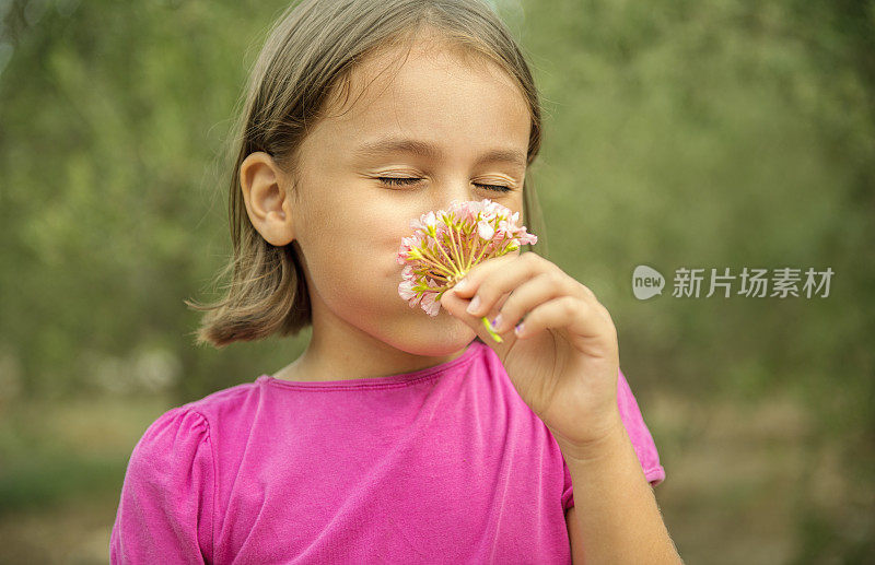 一个快乐的小女孩闻着花香