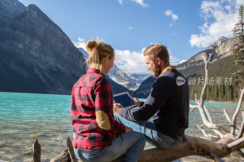 年轻夫妇在湖边咨询数码平板电脑