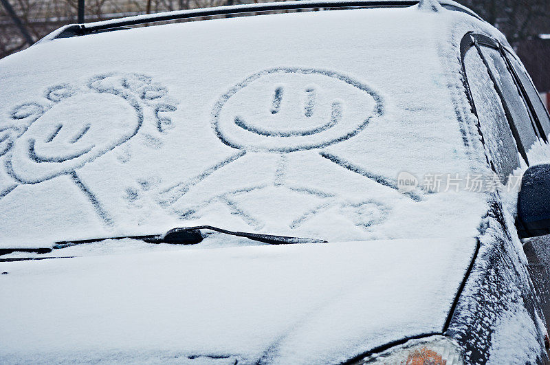 白雪覆盖的汽车挡风玻璃上写着写在雪里的微笑