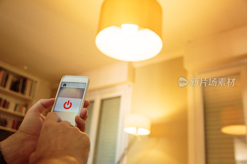 智能家居:男人用手机上的应用程序控制灯光
