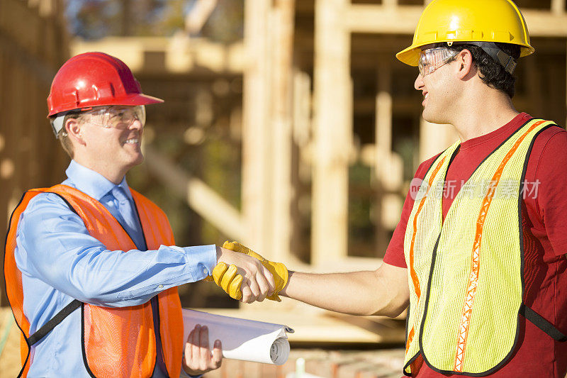 建筑工人与主管在工地讨论工作。建筑。握手。