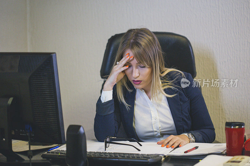 一个愉快的长发女人坐在办公室电脑前的肖像