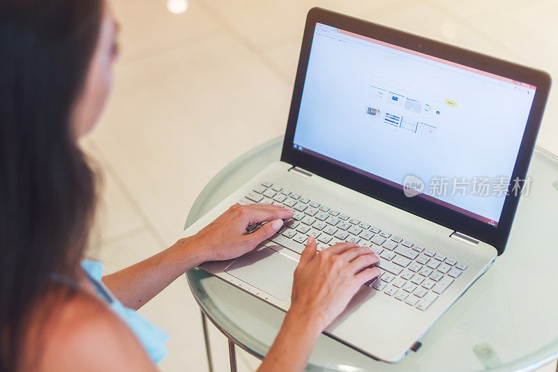 近距离的照片，年轻的商业女性工作在笔记本电脑在白色的办公室