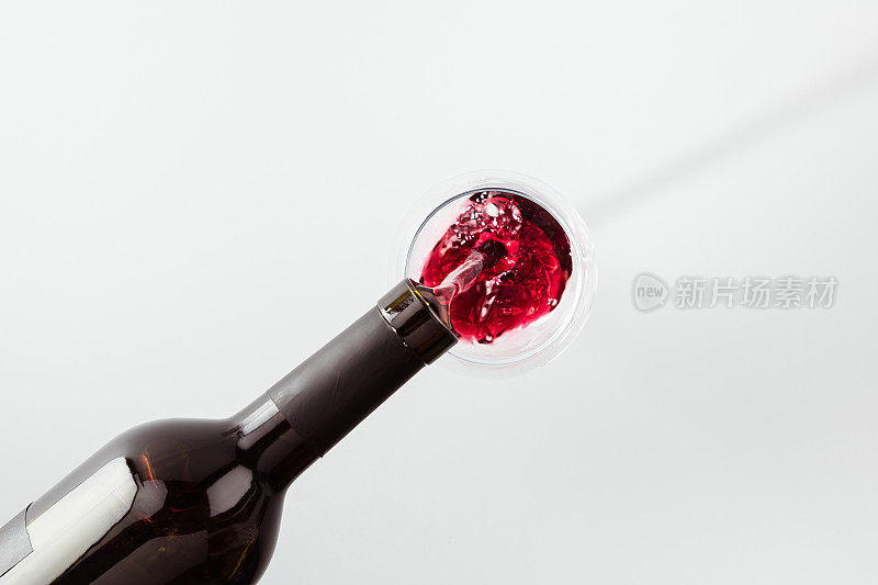 近距离观看红酒从玻璃瓶中倒入孤立的白色