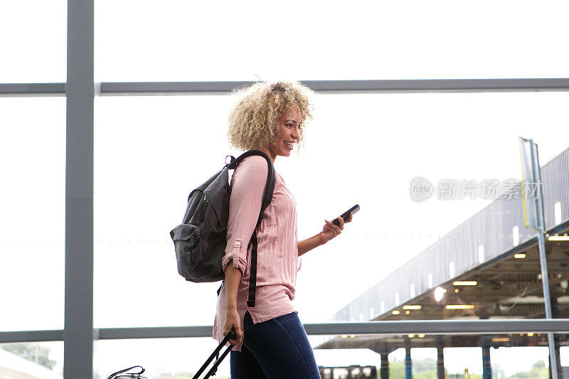 一个微笑的女人拿着手机走在公交车站的肖像