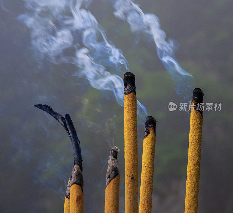 烟棍燃烧与丝一般的烟。亚洲宗教香料祈祷棒