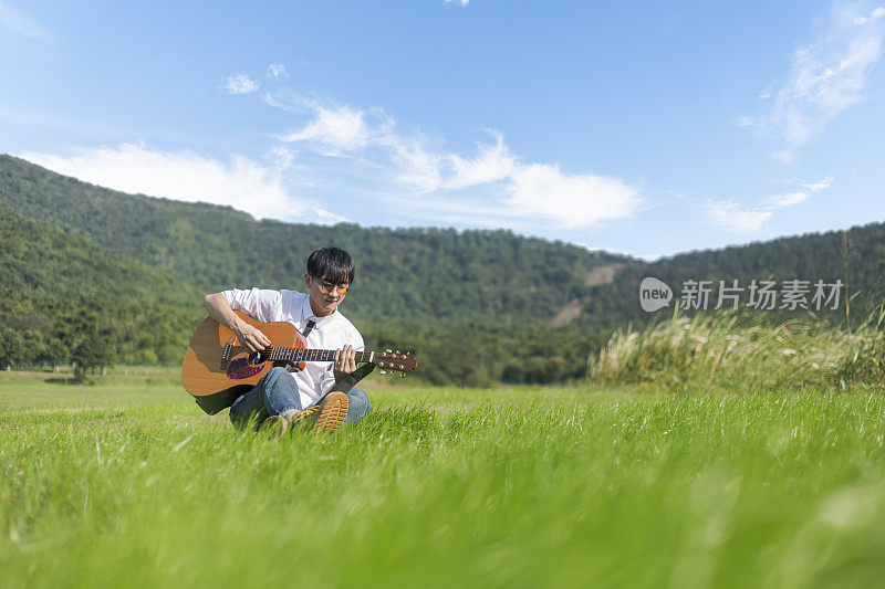 一个年轻人在草坪上弹原声吉他