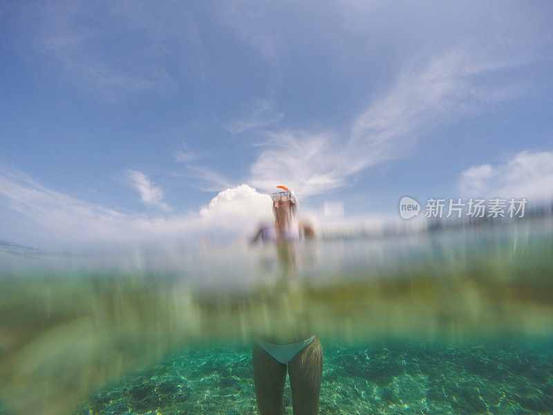 水下拍摄的年轻女子站在热带清澈的海水中度假的人的概念