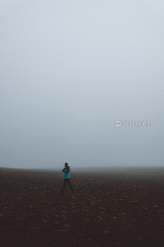 在冰岛，一个女人的剪影走过浓雾弥漫的火山景观