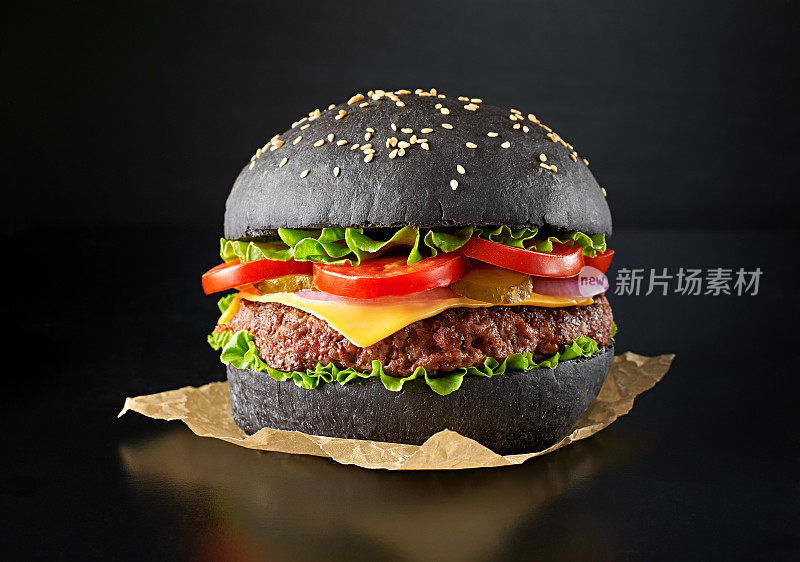 单一黑色汉堡孤立在黑色背景。