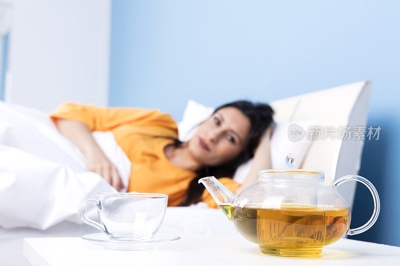 感冒妇女正在床上喝花草茶