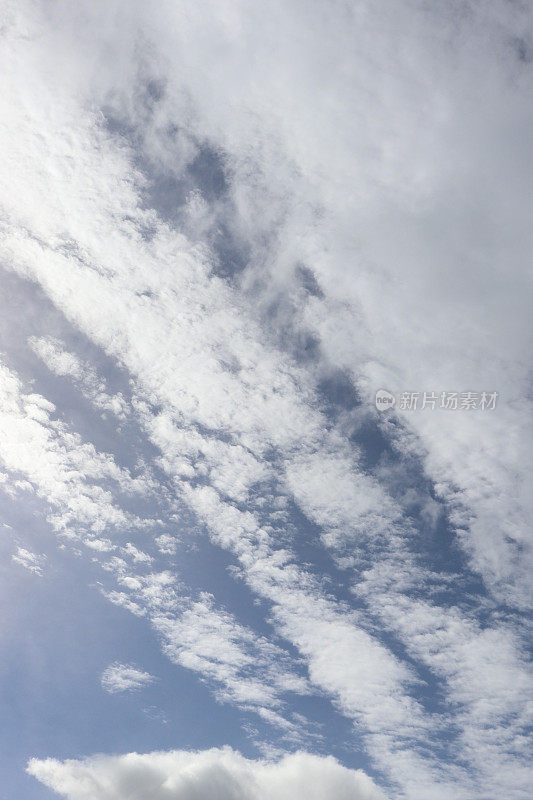 蓝色天空映衬着蓬松、缕缕白云的特写