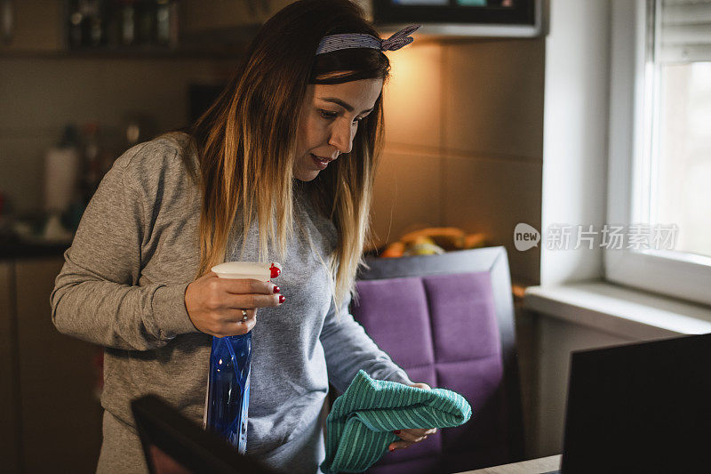 年轻女子小心翼翼地用消毒喷雾清洁桌子