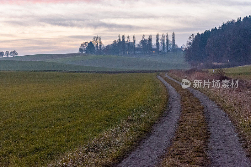 在一个寒冷的秋天傍晚，一条弯曲的乡间小路通往一个农场