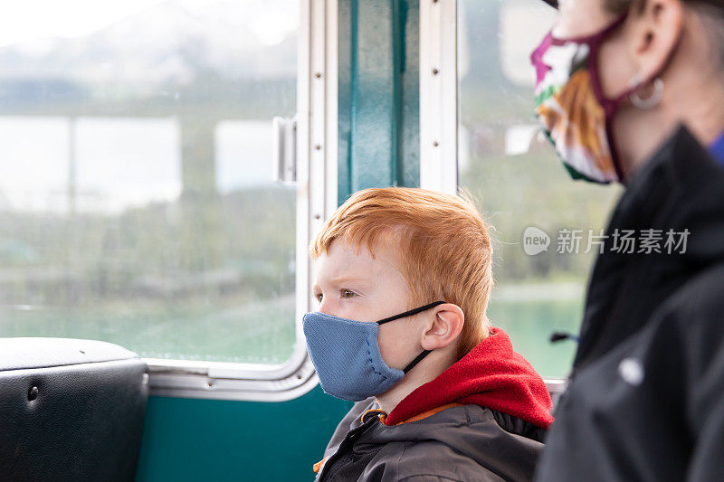 年轻的红发男孩和他的母亲戴着面具在加拿大贾斯帕玛瑞湖游船上
