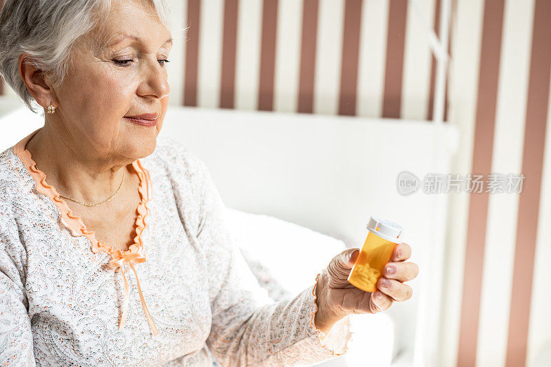 老女人在卧室里，拿着一个药瓶