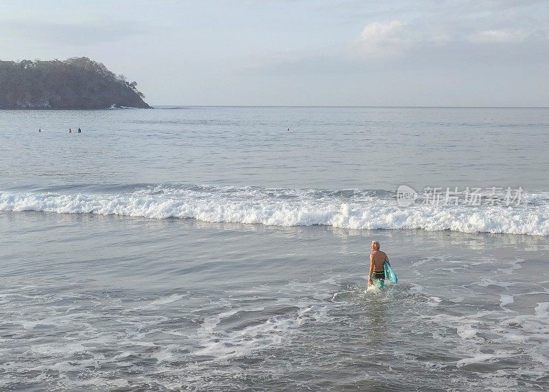 清晨，一个男人带着冲浪板走向大海