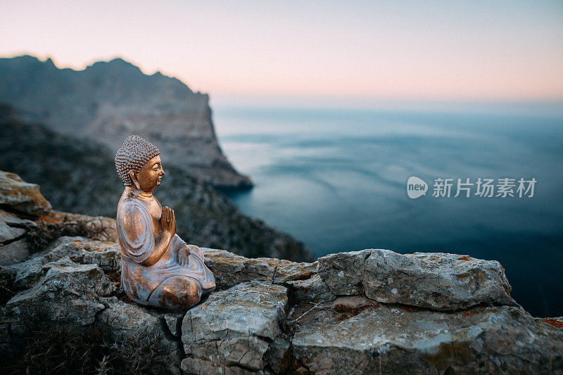 佛像坐在岩石前的山脉和地中海马略卡岛在美丽的日落