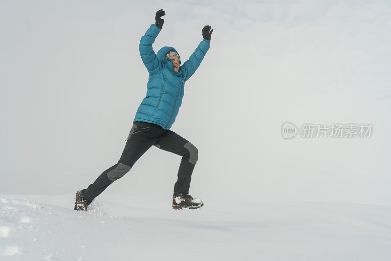 成熟的女人穿着皮大衣在雪地上跳起来