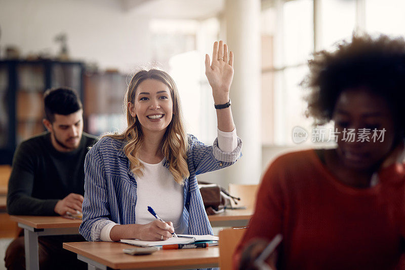 快乐的女学生在教室里举手提问。