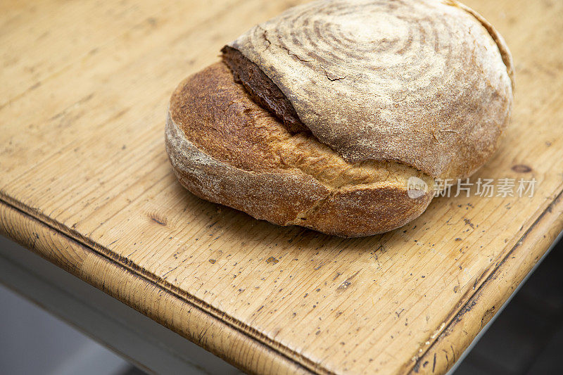 在粗糙的木制餐桌上放着酸面包