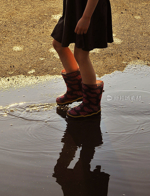 穿着胶靴在水坑里跳的孩子