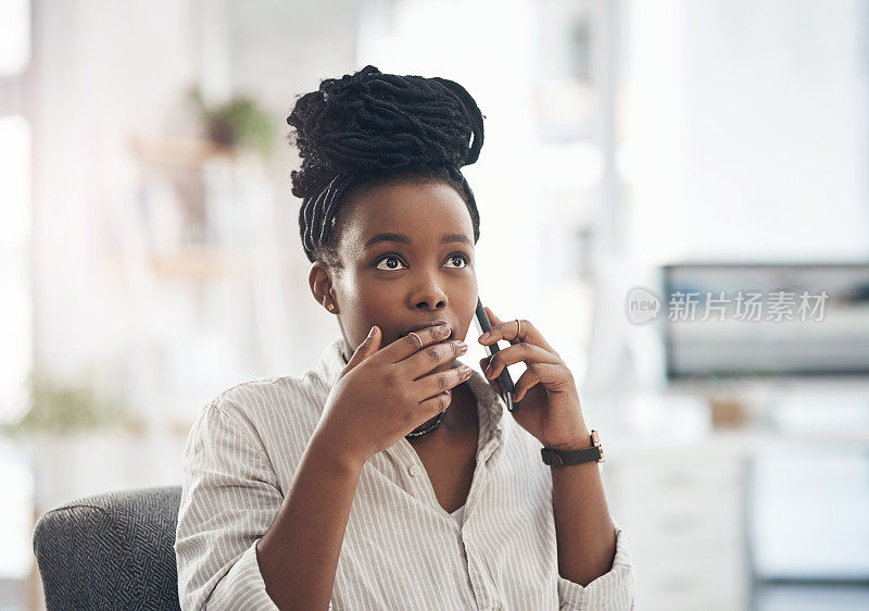 一位年轻的女商人在办公室用智能手机打电话