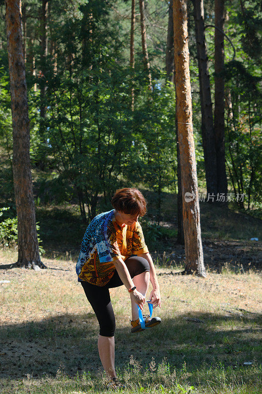 成熟的女人在自然公园用抵抗带锻炼