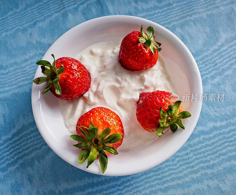 新鲜草莓放在一碗健康的脱脂希腊酸奶里