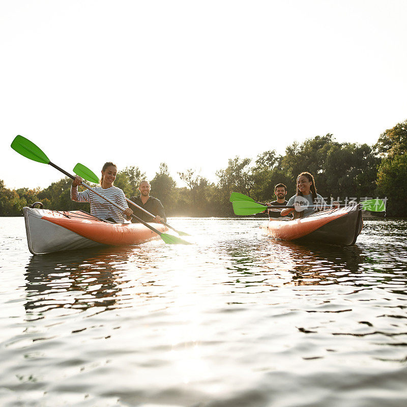 放松的年轻朋友们一起在河上划皮艇，在夏天的一天在户外度过周末