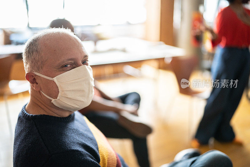 一个成熟男人的肖像在集体治疗在一个共同工作-戴着口罩