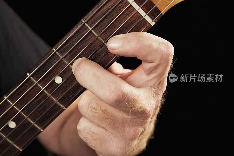 音乐家的左手在电吉他上弹奏和弦的特写
