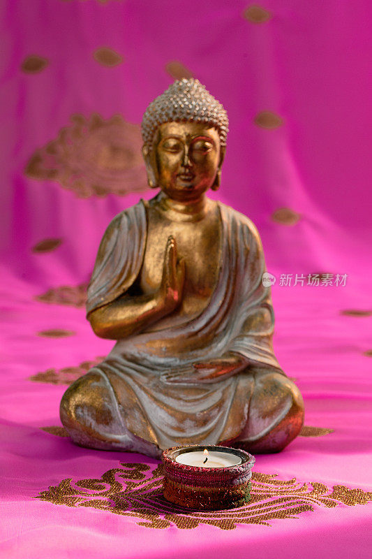 金佛与蜡烛坐在一个彩色的粉红色和金色印度教纱丽绳