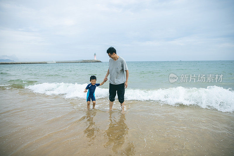 父亲和儿子在沙滩上玩水