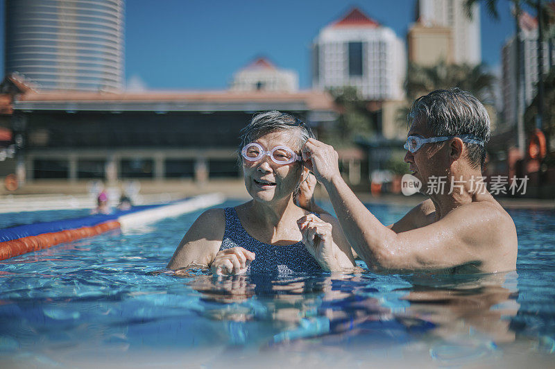 亚洲华人活跃的资深男子戴着游泳护目镜为他的妻子准备上课