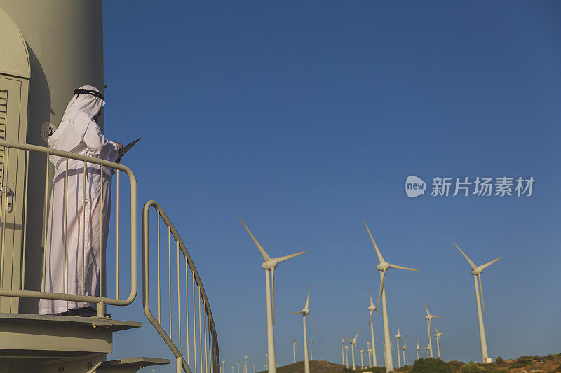 中东商人在农场的风力涡轮机上