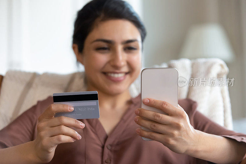 关注女性手中的信用卡和智能手机。