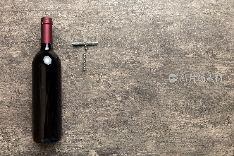 一瓶带开塞钻的红酒放在彩色桌子上。平躺，顶视图与复制空间