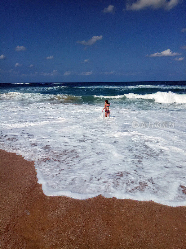 年轻的女孩在阳光明媚的夏日里跳着波浪