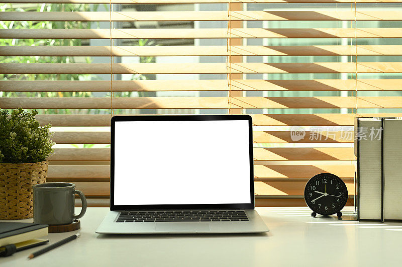 模拟电脑笔记本电脑与白色空显示，闹钟，书和盆栽平板在白色的桌子。