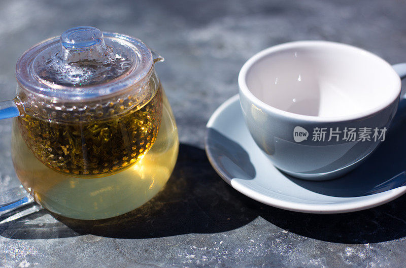绿茶浸泡在玻璃茶壶，干净的杯子，灰色背景