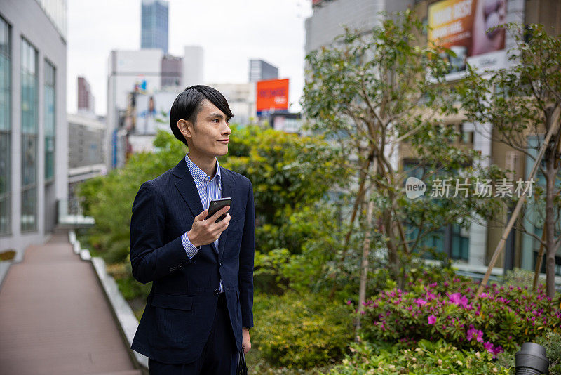 日本商人在城市中行走和使用智能手机