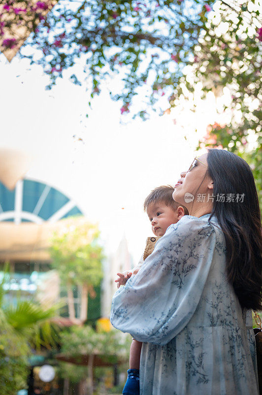 一位妇女抱着她的小男孩在一个美丽的花园里