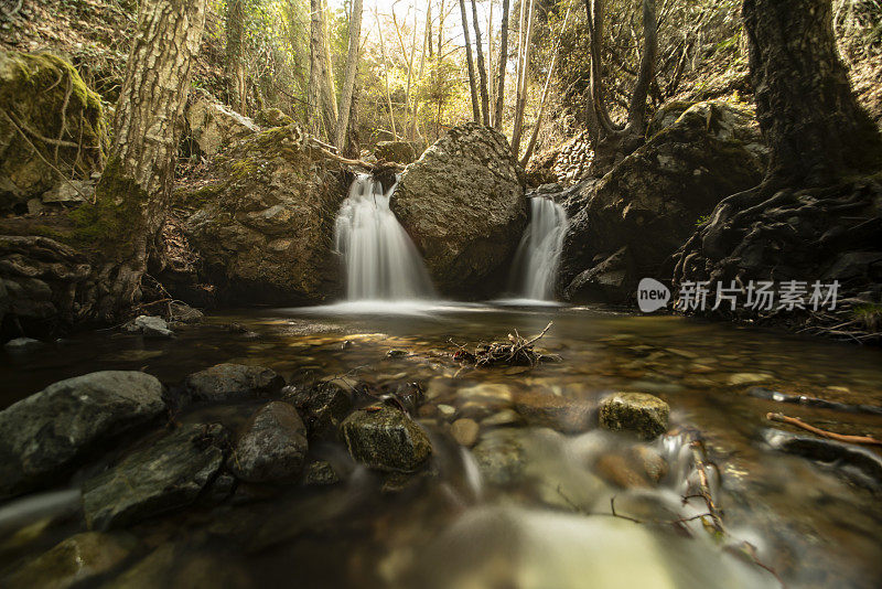 在塞浦路斯的Katalonia小道上，从小溪的中间向双瀑布进入岩石小溪的长曝光