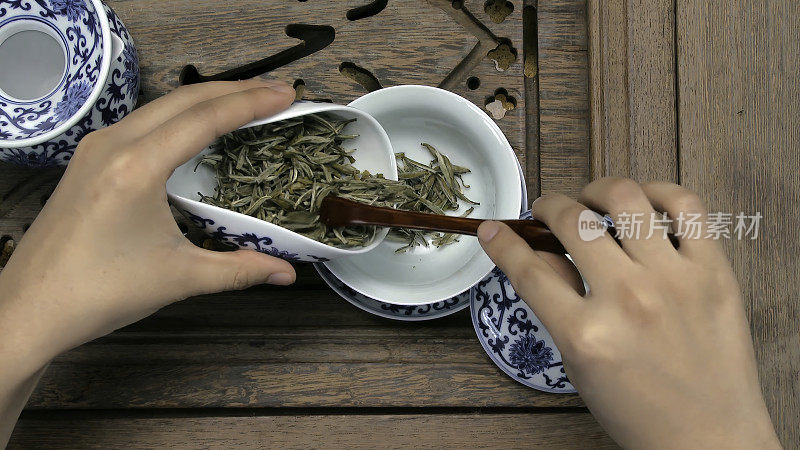 用漏斗把一个棕色的茶壶装满。瓷杯，钢勺。红茶、青茶、普洱茶、乌龙茶、铁观音、参茶、茶