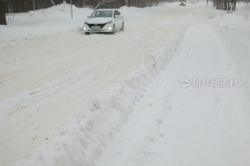 在冬天道路。雪在轨道上漂移。暴风雪中，汽车在白雪覆盖的道路上行驶。