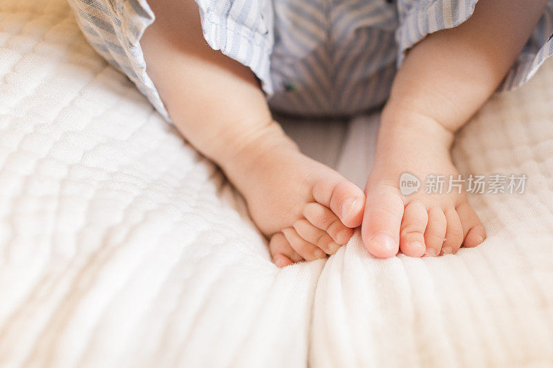 7个月大的男婴，有12个脚趾，穿着海岸服装，躺在一个舒适的海草摩西篮子里，白色亚麻布