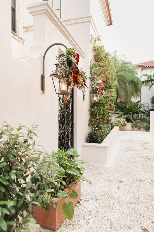 喜庆的红色和绿色圣诞装饰在明亮的白色乡村现代棕榈滩建筑，在2022年12月在南佛罗里达州庆祝快乐和明亮的圣诞节