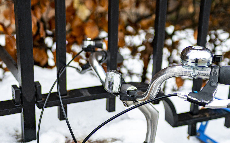 雪地中的公共公园，前景中有一辆自行车靠在栏杆上